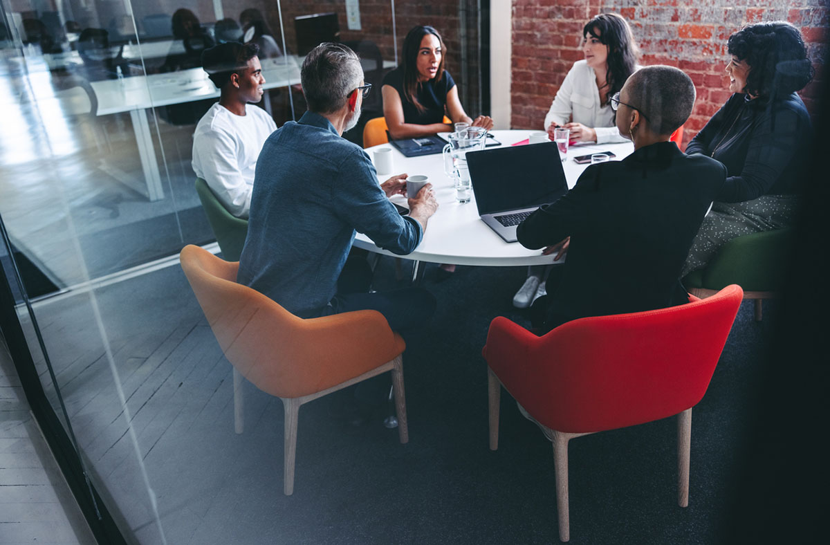 A group of professionals sit at a conference table during a meeting.